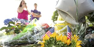 Eine Frau steht mit ihrem Handy vor Blumen und Luftballons