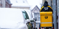 Eine Briefträgerin ist mit ihrem Fahrrad bei starkem Schneefall in der Schweriner Altstadt unterwegs