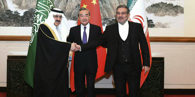 Musaad bin Mohammed al-Aiban und Ali Shamkhani geben sich die Hände, zwischen ihnen steht Wang Yi.
