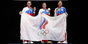 Drei russische Feschterinnen feiern mit der Fahne der russischen olympischen Komitzees ihre Goldmedaille von Tokio
