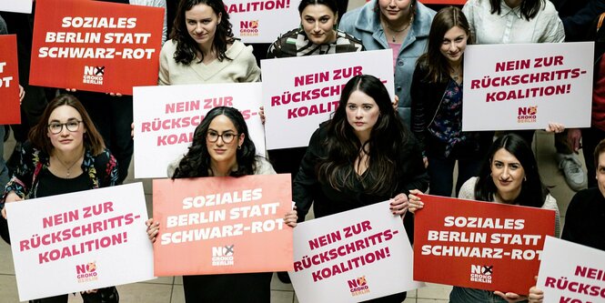 Delegierte halten am Rande der Landesdelegiertenkonferenz der Jusos Berlin im Willy-Brandt Haus Schilder mit der Aufschrift "Soziales Berlin statt Schwarz Rot" und "Nein zur Rückschritts-Koalition" in die Höhe.