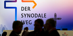 Menschen vor einem Bild, auf dem "Der Synodale Weg" steht