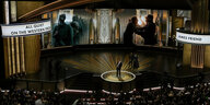 Die Academy-Award-Bühne mit Leinwand-Ausschnitten des Kriegsfilm „Im Westen nichts Neues“. Außerdem Menschen auf der Bühne und im Publikum
