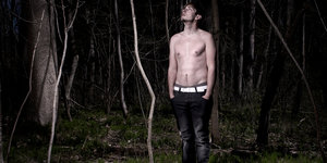 Ein Mann steht mit nacktem Oberkörper im Wald