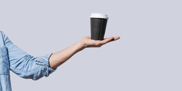 A hand balances a disposable coffee mug