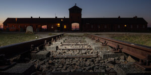 Blick von Eisenbahnschienen auf das Eingangsportal des ehemaligen Konzentrationslagers Auschwitz-Birkenau