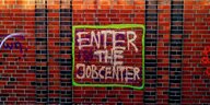 Grafitti "Enter the Jobcenter" an einer Backsteinmauer