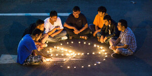 Flüchtlinge sitzen um Kerzen, die das Peace-Zeichen bilden
