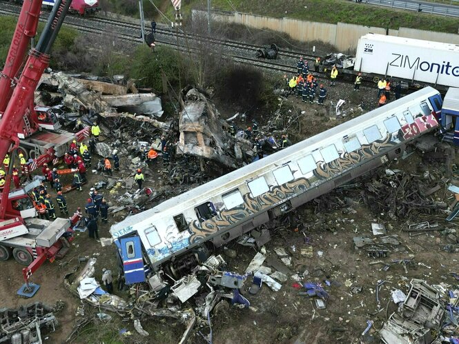 eine Luftbildaufnahme zeigt einen herabgestürzten Waggon, Teile eines verbrannten Zugteils umringt von Feuerwehrleute und Bergungsarbeiter stehen