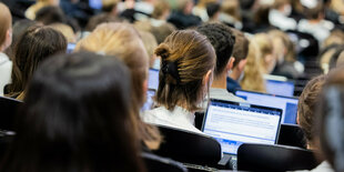 Studierende sitzen in einem Hörsaal und schauen in ihre Laptops