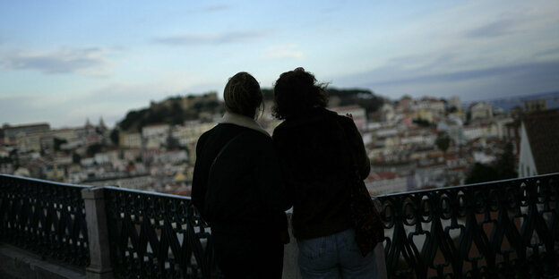 Zwei Frauen schauen über ein Geländer auf die Häuser der Stadt