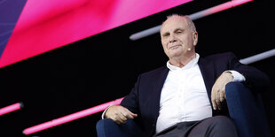 Uli Hoeneß sitzt auf dem Podium einer Veranstaltung