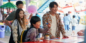 Die Gruppe um Sang-hyun (Song Kang-Ho) lächelnd beim Jahrmarktbesuch.