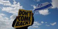 Ein Mann hält eine Israelflagge in der Hand und ein Schild, worauf steht "Don't come back!"