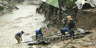 Männer bergen nach schweren Regenfällen Teile aus ihrem zerstörten Haus
