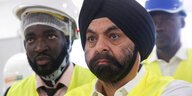 Ajay Banga steht vor anderen Männern mit Helmen