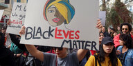 Eine Frau hält ein Plakat hoch wo Black Lives Matter draufsteht