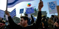 Demonstranten vor dem Brandenburger Tor halten Plakate hoch: "Saving Israel Democracy" und "Keep the court" in den Farben der israelischen Flagge