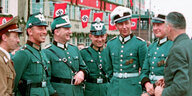 Polizisten und ein Nazi-Funktionär, im Hintergrund Hakenkreuz-Fahnen