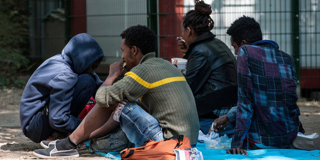 Flüchtlinge sitzen auf dem Boden