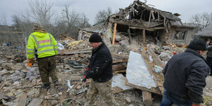Mehrere Männer laufen durch die Überreste eines eingestürzten Hauses