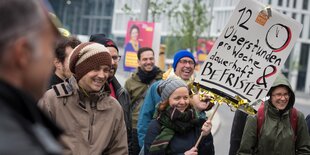 Demonstrant:innen mit einem Plakat auf dem steht "12 Überstunden dauerhaft befristet?"