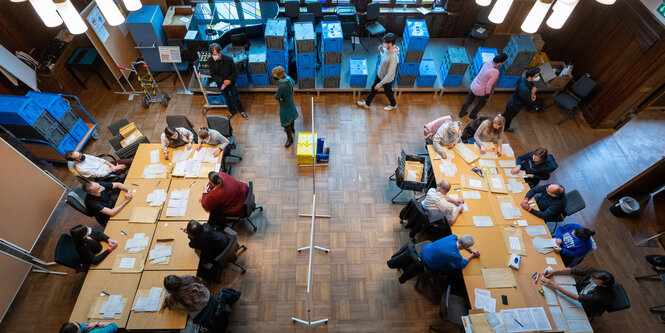 An 2 großen Tischen werden Wahltettel ausgezählt