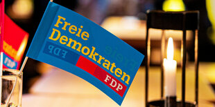 Eine kleine FDP Fahne, dahinter brennt eine Kerze