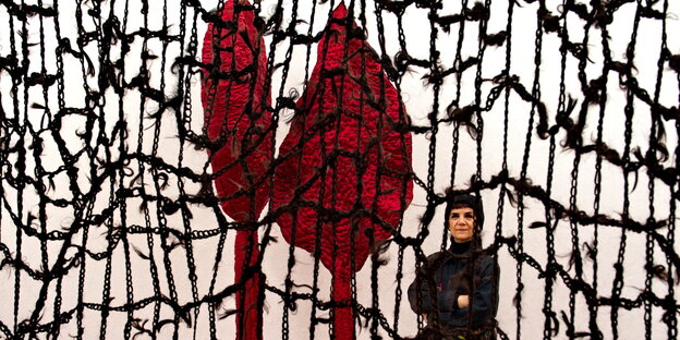 Farkkhondeh Shahroudi vor einem geknüpften Kunstwerk