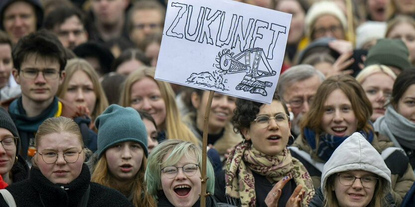 Eine Teilnehmerin der Kundgebung von Fridays for Future hält einen Schild mit dem Wort ·Zukunft· und der Abbildung eines Schaufelradbaggers hoch