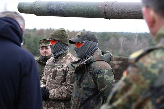 Zwei Soldaten tragen orangefarbene Schutzbrillen und haben ihre Gesichter verhüllt