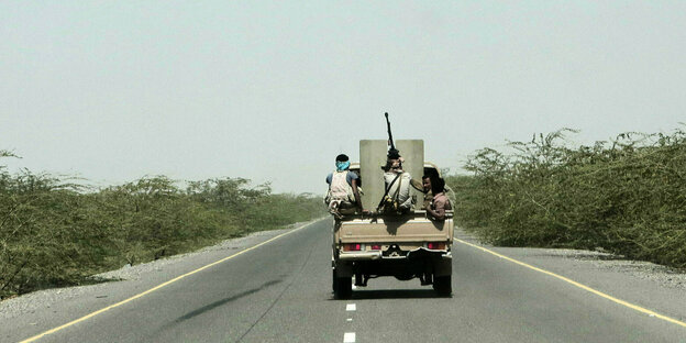 Ein Pick-Up fährt mit bewaffneten Soldaten auf einer Straße