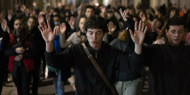 Junge Demonstrant*innen heben in einer Straße in Marseille ihre Arme