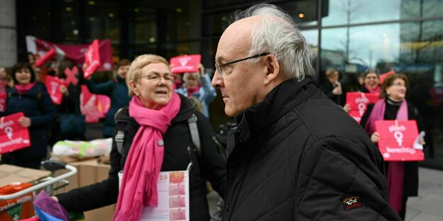 The Bishop of Regensburg walks past protesting women without paying any attention to them