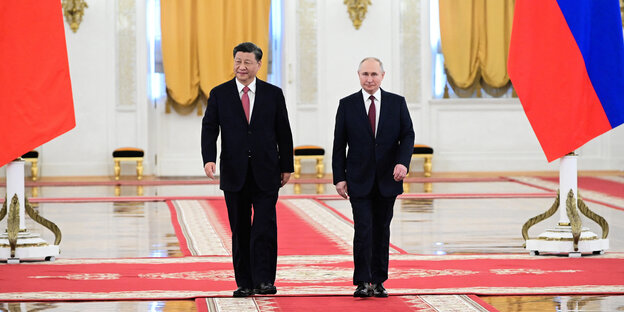 Xi Jinping stands next to Vladimir Putin on the red carpet in the Kremlin