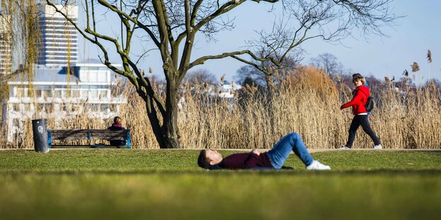 Ein Mann liegt allein in einem Park auf der Wiese und sonnt sich
