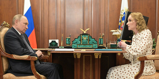 Putin sitzt mit einer Frau an einem Tisch