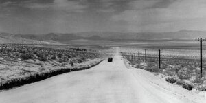 Ein Fahrzeug fährt auf einer Straße durch die Wüstenlandschaft Mojave