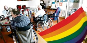 Eine Regenbogen-Fahne weht im Gemeinschaftsraum einer Wohngemeinschaft für homosexuelle Senioren in Berlin, die sich um den Esstisch zum Mittagessen versammelt haben.