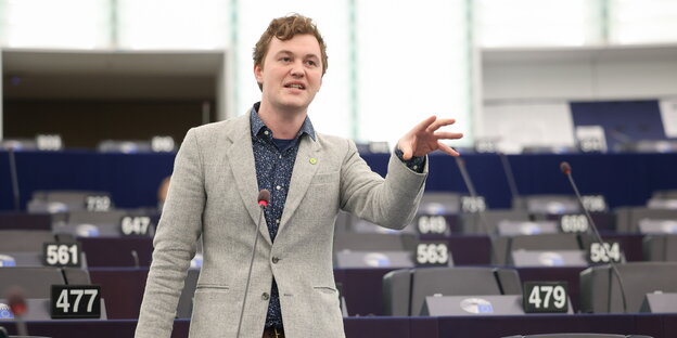 Ein junger Mann streckt die Hand greifend aus im Plenarsaal der EU