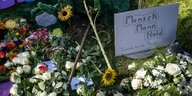 Ein Plakat mit der Aufschrift «Mensch, Mann, Held» liegt neben Blumen an einem Grab