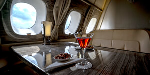 Nüsse und ein Glas mit Alkohol stehen auf einem Tisch in einem Flugzeug