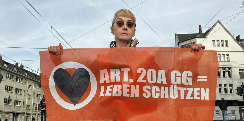 Frau hält Plakat von Letzte Generation in die Kamera