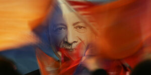 Erdogan-Supporter schwenken Flaggen vor einem Plakat mit dem Portrait von Erdoğan