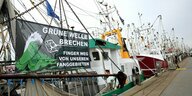 Ein Protestbanner mit dem Text ·Grüne Welle brechen - Finger weg von unseren Fanggründen an einem Kutter im Hafen von Büsum