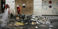 Feuerwehrmänner löschen das Feuer eienes brennenden Müllhaufens