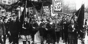 Die Aufnahme aus dem Jahr 1919 zeigt einen Demonstrationszug mit Frauen an der Spitze, der die USPD unterstützt.