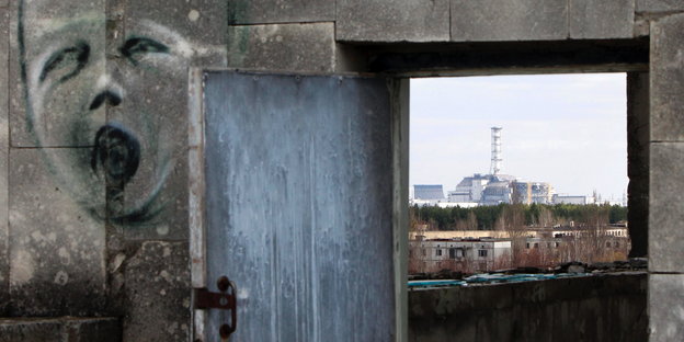 Durch eine Tür sieht man den Sarkophag, unter dem sich das Atomkraftwerk Tschernobyl befindet