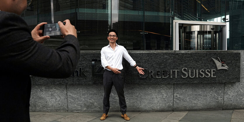 Eine Person lässt sich vor einem Bankgebäude der Creit-Suisse fotografieren