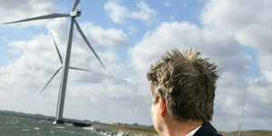 Robert Habeck blickt auf Windkraftanlagen an einer Küste